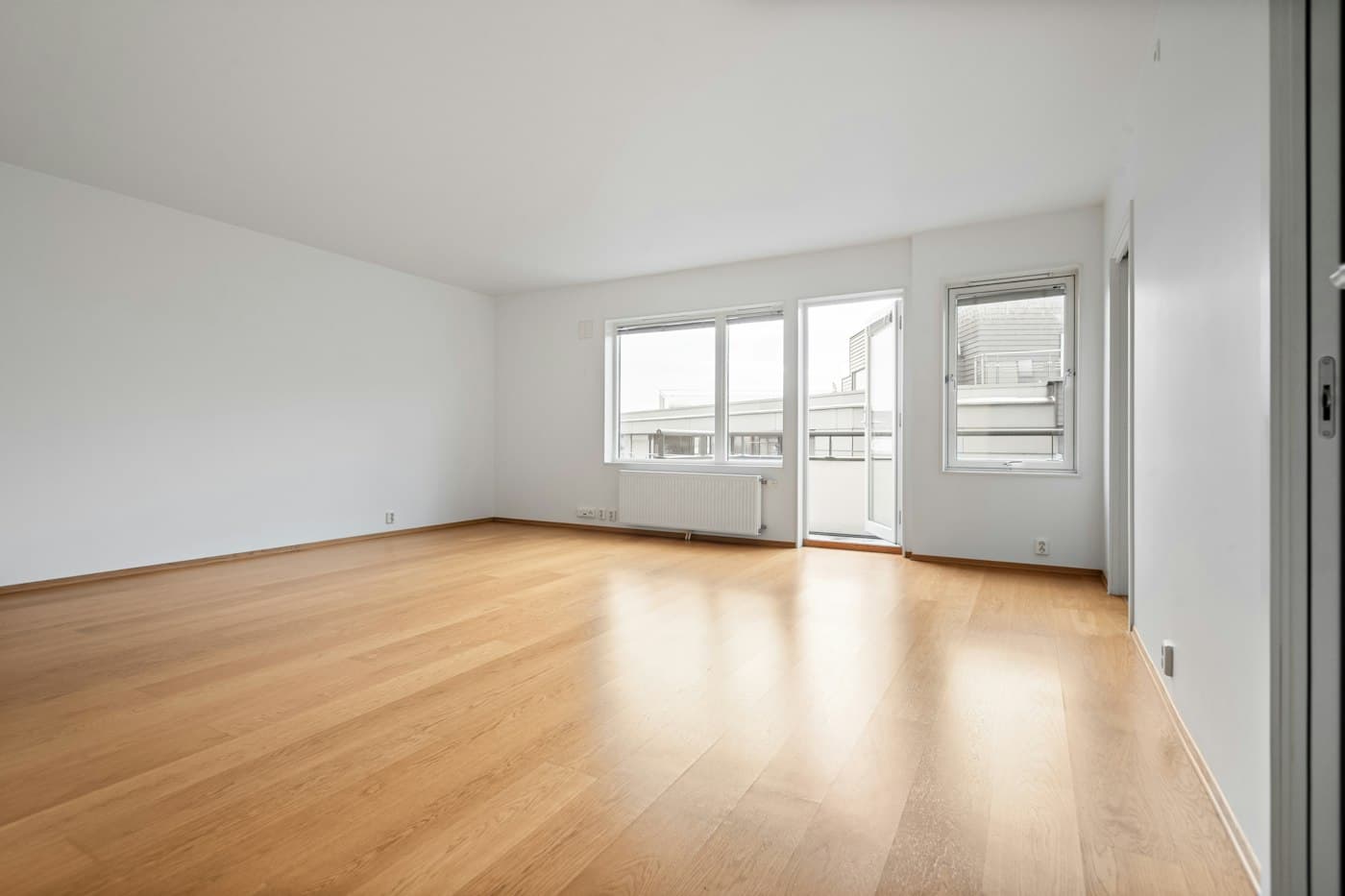 BEISPIEL-FOTO: leerer heller Raum mit Holzboden und großem Fenster