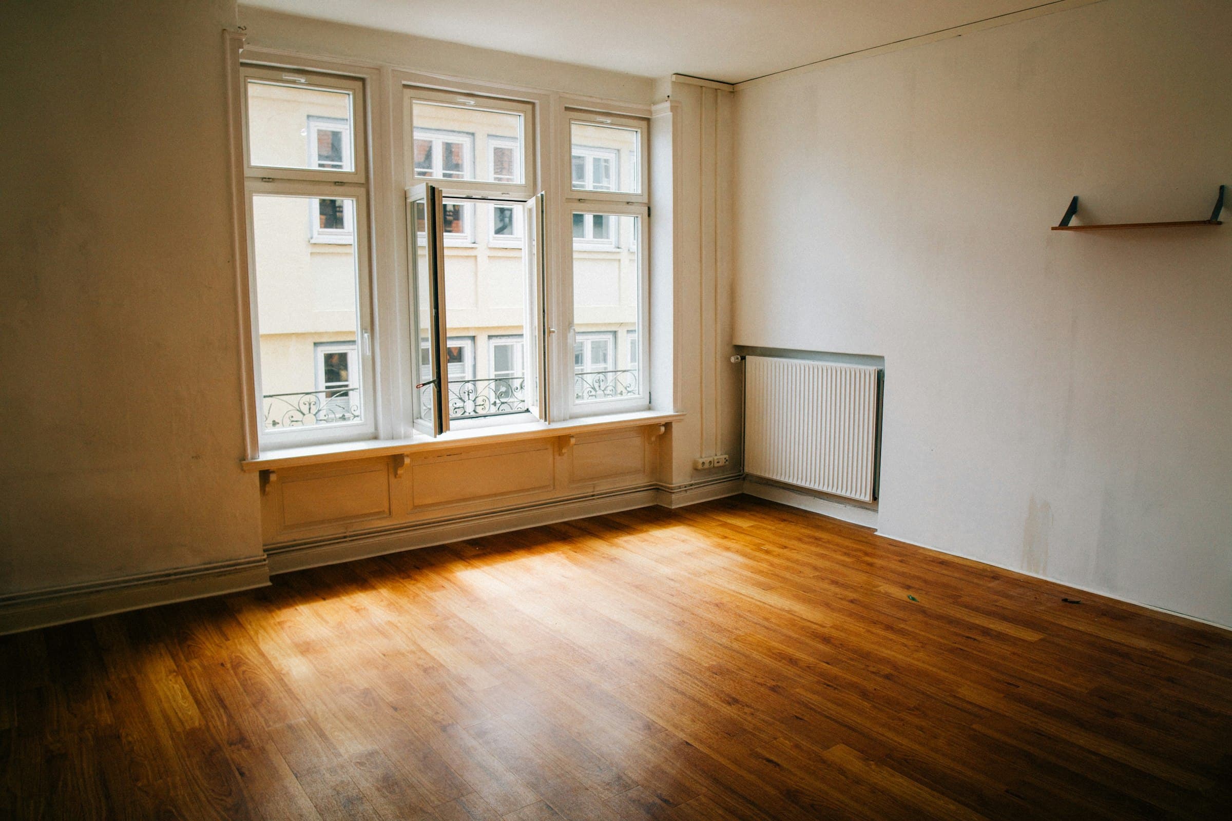 BEISPIEL-FOTO: leerer Altbauraum mit Holzboden und hohen Sprossenfenstern