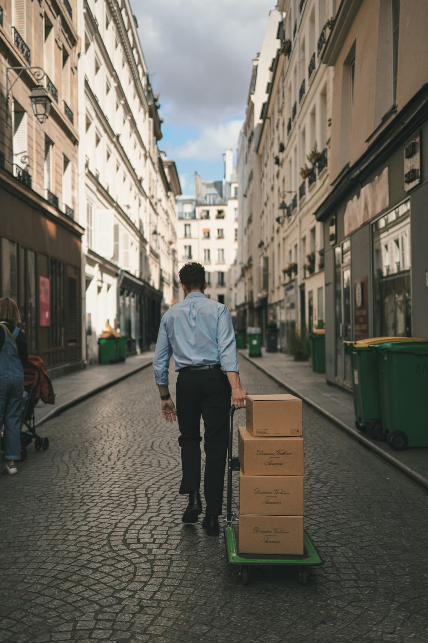 BEISPIEL-FOTO: Mann schiebt eine Sackkarre mit Kartons durch eine Altstadtgasse