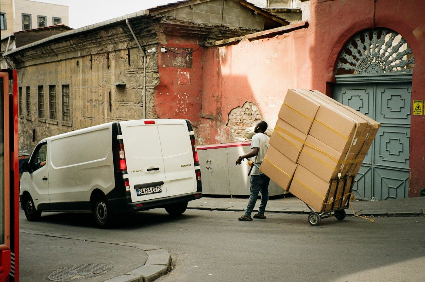 BEISPIEL-FOTO: Umzugshelfer mit Sackkarre und Kartons vor einem Transporter